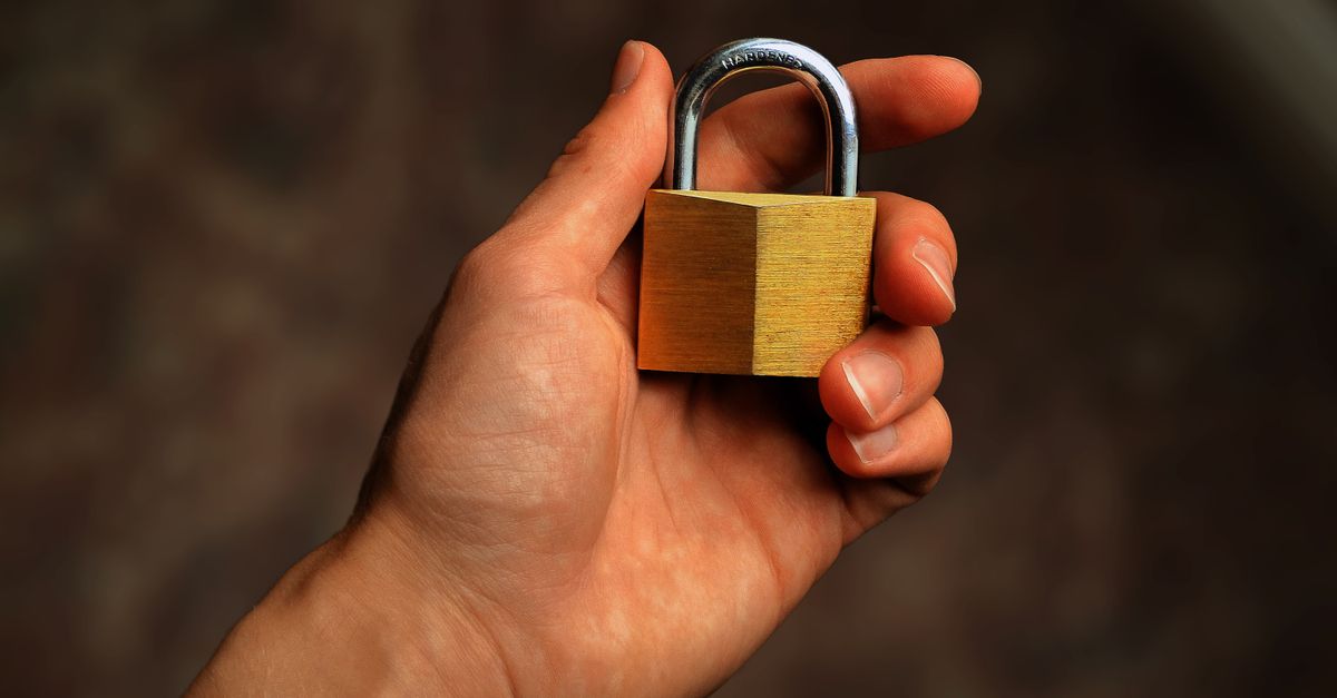 Hand holding a brass padlock, symbolizing security and protection